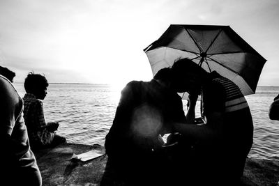 People sitting on beach against clear sky