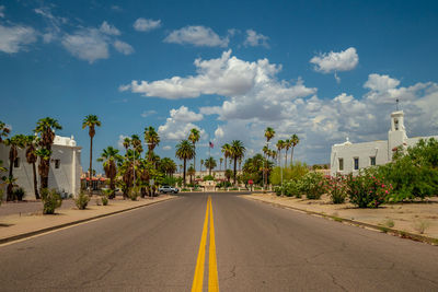 Road leading towards city against sky