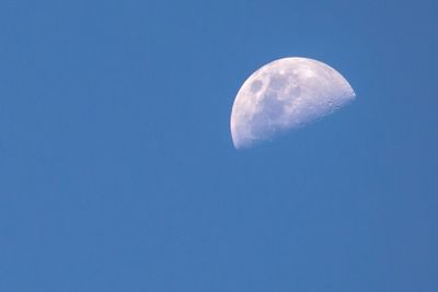 Low angle view of moon against clear blue sky