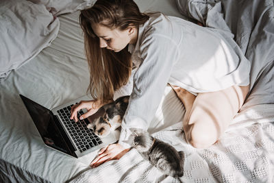 Work from home, remote online work, home office. woman working on laptop in bed and playing with