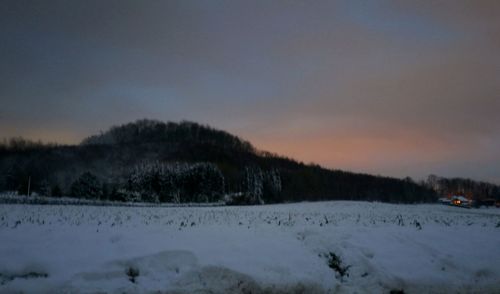 Scenic view of snow field against sky at sunset