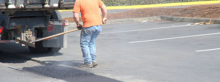 Low section of man working on road in city