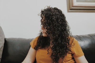 Woman with curly hair sitting on sofa at home