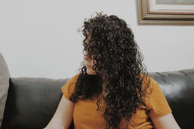 Woman looking away while sitting on sofa at home