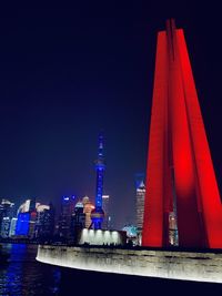 Illuminated buildings against clear blue sky at night