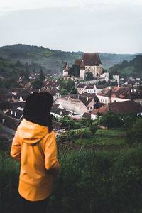 Rear view of man looking at buildings against sky
