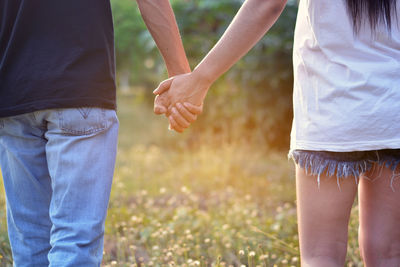 Midsection of couple holding hands