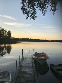 Pier on lake against sky during sunset