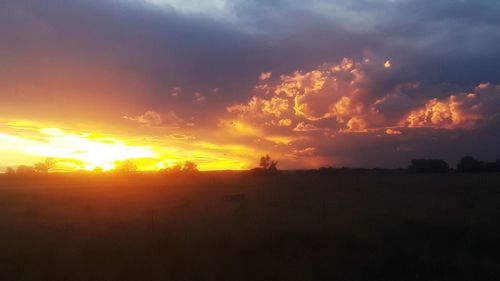 Scenic view of silhouette field against sky during sunset