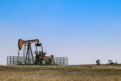 Traditional windmill on field against clear blue sky