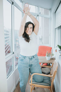 Portrait of young woman standing by window