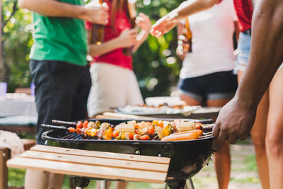 Midsection of people enjoying by barbecue grill