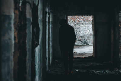 Rear view of silhouette man standing in abandoned building