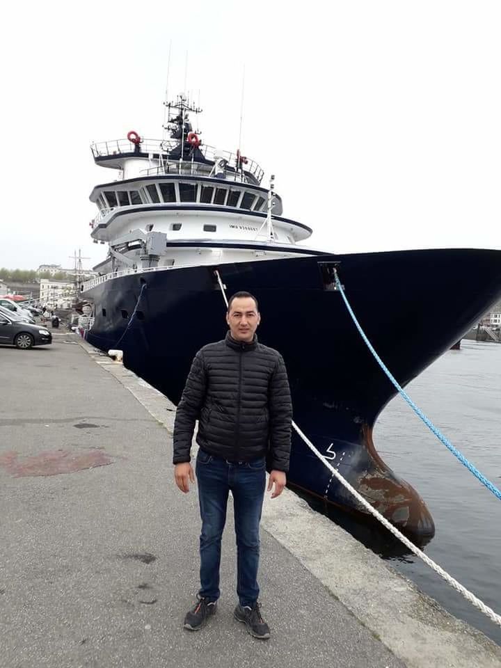 transportation, mode of transportation, nautical vessel, one person, real people, men, standing, front view, full length, looking at camera, water, sky, casual clothing, portrait, day, hands in pockets, adult, leisure activity, outdoors, sailor, luxury