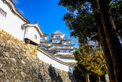 Low angle view of trees and building against sky