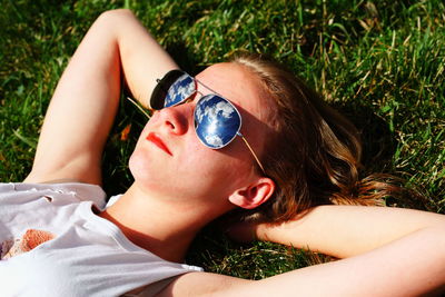 High angle view of woman in sunglass relaxing on grassy field