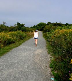 Rear view of woman standing on road against sky