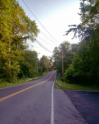 Empty road amidst trees against sky