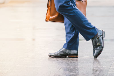 Low section of businessman with suitcase walking on street