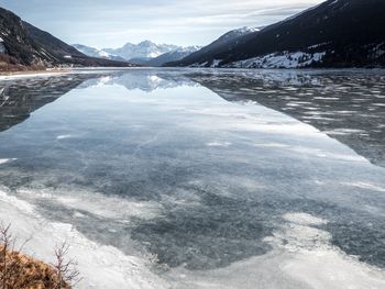 Scenic view of lake by snowcapped mountains against sky