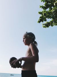 Girl looking at sea against clear sky