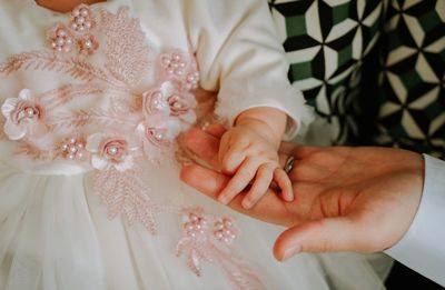 Midsection of baby holding hands with dad