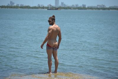 Rear view of shirtless man standing in sea