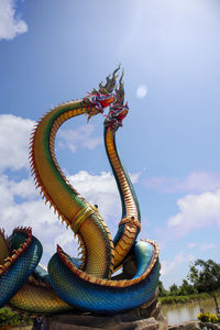 Low angle view of dragon sculpture against blue sky