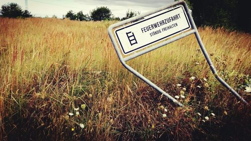 Information sign on field against sky
