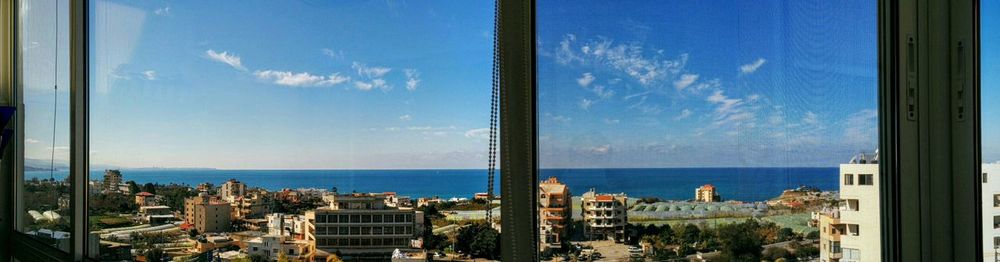 Panoramic view of city by sea against sky seen through window