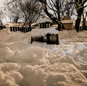 Snow covered field by building against sky