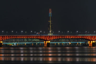 Illuminated bridge over river at night