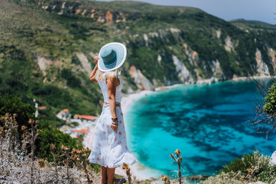 Rear view of woman standing by sea