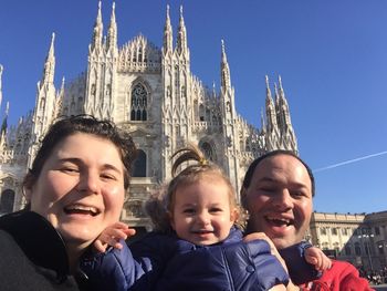 Portrait of happy family standing against milan cathedral