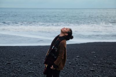 Woman standing on beach against sea