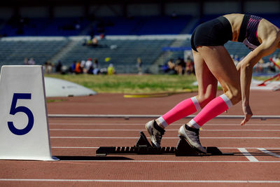 Girl athlete in compression socks running from starting blocks