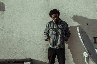 Portrait of young man standing against wall