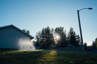 Grassy field by house against clear sky