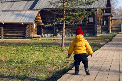 Boy in a yellow jacket walks in the village in the fall