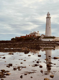 Lighthouse by sea against sky