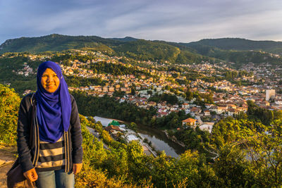 Portrait of young woman standing against mountain