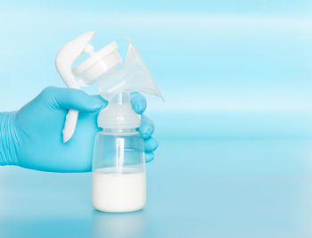 Close-up of hand holding bottle against blue background