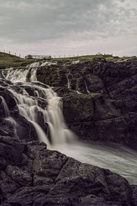 Scenic view of waterfall against sky
