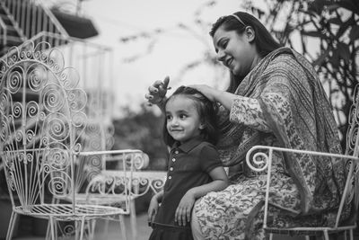 Smiling mother tying daughter hair