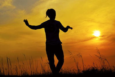 Silhouette woman dancing on land against sky during sunset