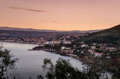 Scenic view of river by city against sky during sunset