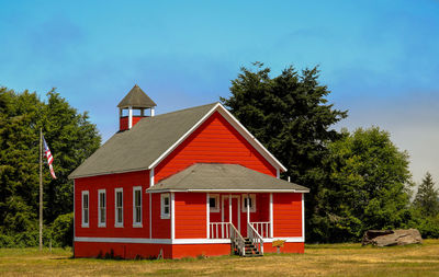 Red house on field against clear sky