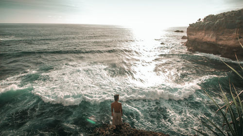 Rear view of man looking at sea against sky