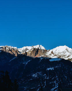 Scenic view of snowcapped mountains against clear blue sky