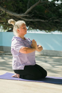 Side view of young woman sitting at beach